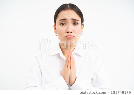 Upset young saleswoman, asian woman holds hands in pray, begs you, asks for favour with sad face, pleading, standing over white background 101749179