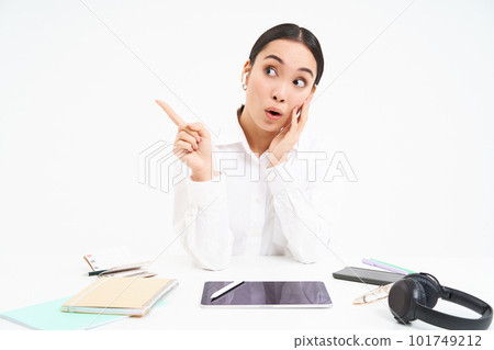 Portrait of asian businesswoman sits in office with tablet, points left and smiles, shows advertisement, office banner, white background 101749212