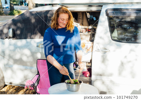Middle aged nomad woman cooking salad outside her camper van in the forest camp with her cockapoo puppy pet during road trip. Best friend. Enjoying free lifestyle, travel vacation. Travel with pets. Middle aged nomad woman cooking salad outside her camper van in the forest camp with her cockapoo puppy pet during road trip. Best friend. Enjoying free lifestyle, travel vacation. Travel with pets. 101749270