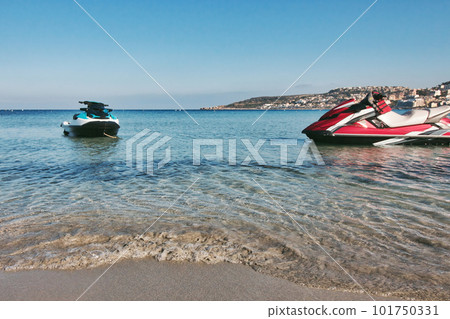 A couple of recreational power jet skis with no people at the water's edge of a sandy beach shoreline in the Mediterranean sea A couple of recreational power jet skis with no people at the water's edge of a sandy beach shoreline in the Mediterranean sea 101750331