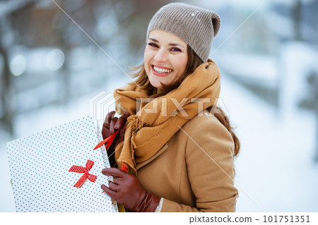 happy stylish female in brown hat and scarf in camel coat 101751351