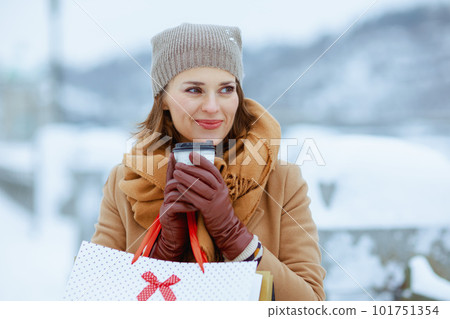 happy modern female in brown hat and scarf in camel coat 101751354