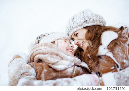smiling elegant mother and child laying in snow smiling elegant mother and child laying in snow 101751391
