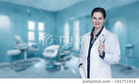 Doctor dentist woman with a tool in her hands stands . Doctor dentist woman with a tool in her hands stands . 101751413