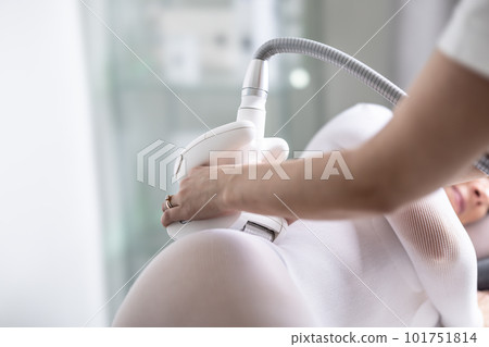 Female skincare treatment practitioner performs LPG endermology treatment of hips of a female patient 101751814