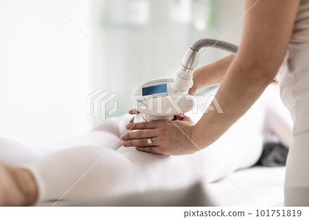 Cosmetics beautician holds LPG endermology device on body of a client lying on a cosmetics studio table 101751819
