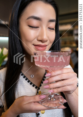 Contented woman smelling a cocktail in the glass 101753221