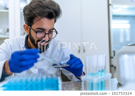 Scientist man testing chemical sample in flask at laboratory with lab glassware. 101753324