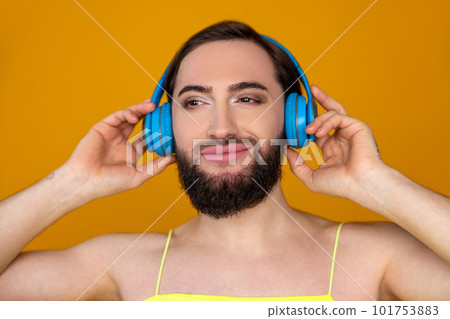 Closeup of smiling satisfied transgender person with beard listening to music via blue headphones Closeup of smiling satisfied transgender person with beard listening to music via blue headphones 101753883