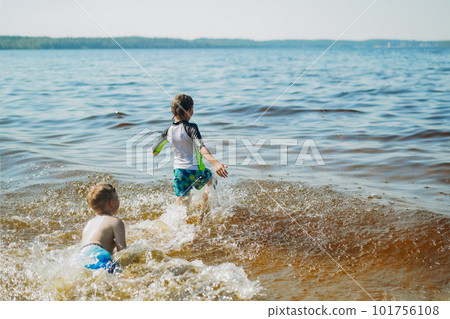 cute caucasian boy running into water with splashes and laughter. Vacation on sea side. Happy childhood. Image with selective focus cute caucasian boy running into water with splashes and laughter. Vacation on sea side. Happy childhood. Image with selective focus 101756108