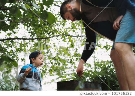 childr and father grilling meat on barbecue having picnic outdoors 101756122