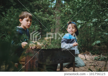 children grilling meat on barbecue having picnic outdoors 101756123