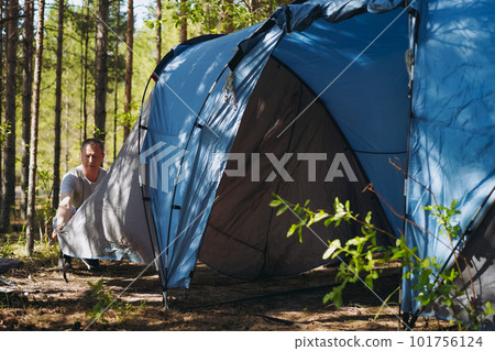 caucasian man wearing a hat putting up a tent. Family camping concept 101756124