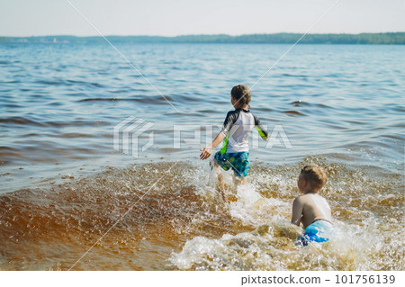 cute caucasian boy running into water with splashes and laughter. Vacation on sea side. Happy childhood. Image with selective focus cute caucasian boy running into water with splashes and laughter. Vacation on sea side. Happy childhood. Image with selective focus 101756139