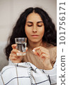 Beautiful young woman holding a pill and water 101756171