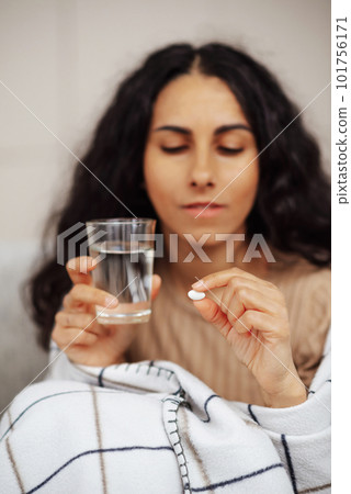 Beautiful young woman holding a pill and water Beautiful young woman holding a pill and water 101756171