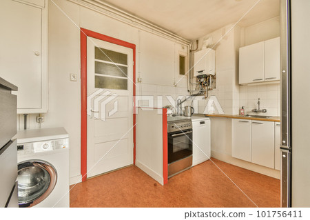 a small kitchen with an oven and dishwasher in the doord doorway leading to another room where there is a washing machine 101756411