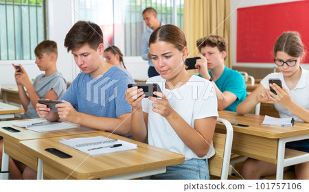 Pupils with smartphones sitting in class 101757106