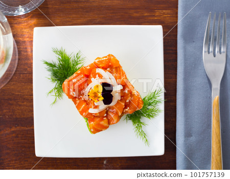 Cube of delicious salmon tartare garnish with avocado on plate at cafe Cube of delicious salmon tartare garnish with avocado on plate at cafe 101757139