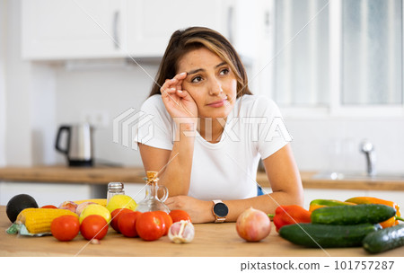 Sad woman looking at vegetable at kitchen, dieting problems 101757287