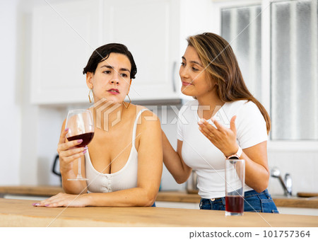 Woman consoling the depressed woman at table in kitchen 101757364