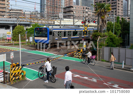 A train passing a railroad crossing in the morning with cyclists and pedestrians waiting A train passing a railroad crossing in the morning with cyclists and pedestrians waiting 101758080