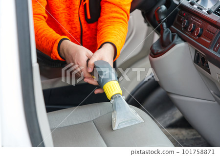 Handyman vacuuming car front textile seat with vacuum cleaner. man cleaning work machine Handyman vacuuming car front textile seat with vacuum cleaner. man cleaning work machine 101758871