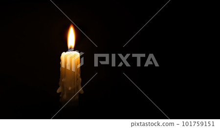 Burning wax candle against a black background Burning wax candle against a black background 101759151