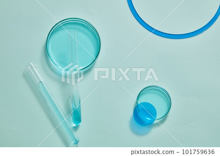 Against a light blue background, petri dishes and test tubes filled with blue fluid are displayed. Blank space can be used to show cosmetic product 101759636