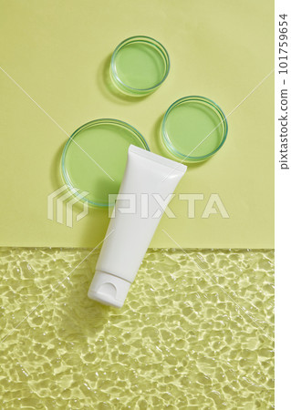 A white tube without label displayed with petri dishes in different sizes on pastel background. Production of natural skincare products in the laboratory 101759654