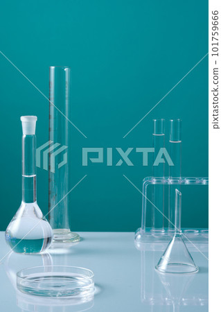A glass petri dish filled with liquid decorated with test tubes and many laboratory glassware. Minimal blue background. Empty space in the middle for product presentation A glass petri dish filled with liquid decorated with test tubes and many laboratory glassware. Minimal blue background. Empty space in the middle for product presentation 101759666