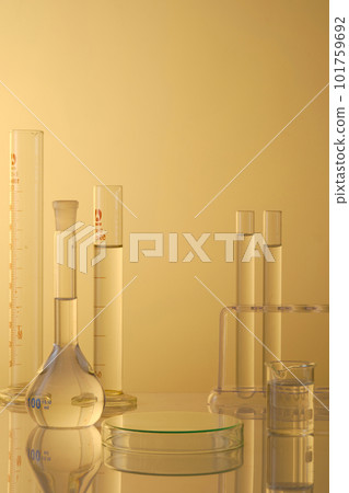 Minimal concept with laboratory glassware - test tubes and beaker filled transparent liquid, petri dishes upside down form an empty platform to display products. Front view Minimal concept with laboratory glassware - test tubes and beaker filled transparent liquid, petri dishes upside down form an empty platform to display products. Front view 101759692
