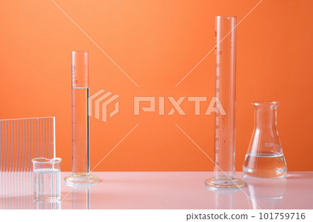 Blank minimal concept with laboratory equipment containing colorless liquid and ribbed acrylic sheets on orange neon background. Empty space in the middle for cosmetic product presentation Blank minimal concept with laboratory equipment containing colorless liquid and ribbed acrylic sheets on orange neon background. Empty space in the middle for cosmetic product presentation 101759716