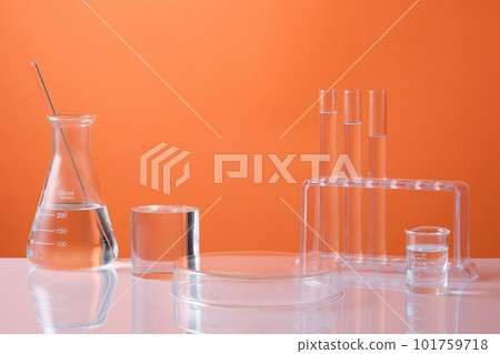 Front view of laboratory equipment - erlenmeyer flask, test tubes and beaker filled colorless liquid and cylinder podium for product presentation on orange background. Science and medical background Front view of laboratory equipment - erlenmeyer flask, test tubes and beaker filled colorless liquid and cylinder podium for product presentation on orange background. Science and medical background 101759718