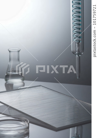 Laboratory glassware containing transparent solution and ribbed acrylic sheets decorated on back lit background. Science laboratory research and development concept 101759721