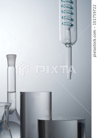 Closeup view of lab glassware filled transparent solution and cylinder podiums for cosmetic product presentation on light background. Concept: research, biochemistry, nature, pharmaceutical medicine Closeup view of lab glassware filled transparent solution and cylinder podiums for cosmetic product presentation on light background. Concept: research, biochemistry, nature, pharmaceutical medicine 101759722
