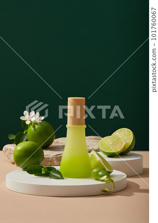 White round podium with Lime slices and peels, flowers and green leaves placed on. A jar without label for branding mockup. Lime (Citrus aurantiifolia) essential oil has the ability to treat acne 101760067