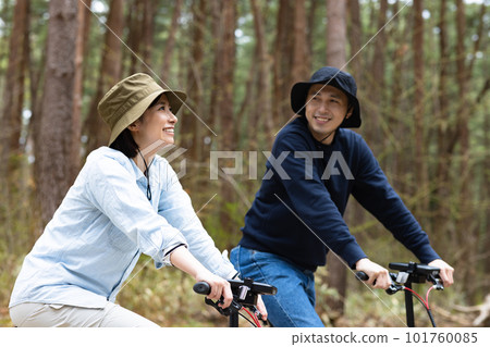 Couple riding an electric bike in the woods Couple riding an electric bike in the woods 101760085
