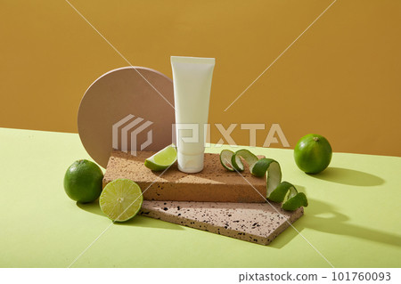 Unlabeled plastic bottles placed on rectangle brick platform, limes and limes spiraling on a yellow background. Mockup scene cosmetic, facial cleanser of limes extract 101760093