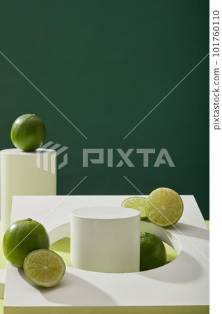 Blank minimal background with white empty podium, geometric object and fresh limes (Citrus aurantifolia) decorated on dark background. Space for product presentation with natural extracts 101760110
