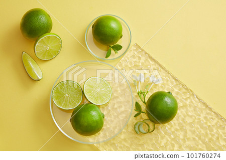 An acrylic sheet with a glass petri dish of Lime slices and peel with white flowers placed on. Using skin care product extracted from Lime (Citrus aurantiifolia) for brighter skin An acrylic sheet with a glass petri dish of Lime slices and peel with white flowers placed on. Using skin care product extracted from Lime (Citrus aurantiifolia) for brighter skin 101760274