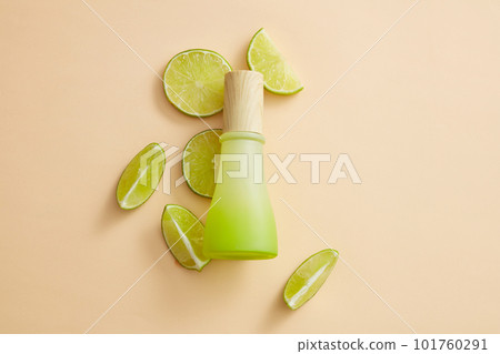 Some Lime slices are arranged with a blank label jar with wooden cap against pastel background. Lime (Citrus aurantiifolia) essential oil can slow down the physical effects of aging 101760291