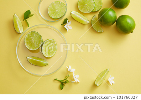 A round transparent podium and glass petri dish decorated with Lime slices and small flowers. Copy space to add your text. Product presentation of Lime (Citrus aurantiifolia) extract 101760327