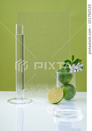 Blank minimal background with lab glassware, fresh lime and flower decorated on green background. Empty space for cosmetic product with ingredient from lime presentation. Copy space. 101760520
