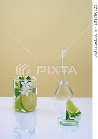 Scene for advertising cosmetic with laboratory concept. Fresh lime slices, leaves and flower in beaker, volumetric flask and petri dish filled transparent liquid. Empty space for product presentation 101760523