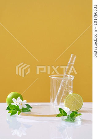 Scene for the display cosmetic with fresh limes, flower and leaves on yellow background and lab glassware. Lime extract is rich in minerals and vitamin C for good skin care. 101760533