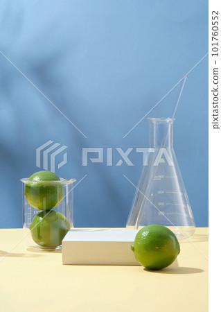 Fresh limes on blue background with lab glassware and white empty podium. Space for display cosmetic of lime extract. Line essential oil is great for the skin, treating acne and controlling oily skin Fresh limes on blue background with lab glassware and white empty podium. Space for display cosmetic of lime extract. Line essential oil is great for the skin, treating acne and controlling oily skin 101760552