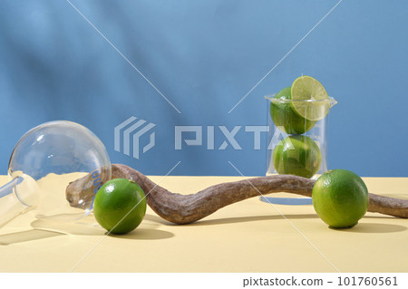 Minimal concept for display product with fresh limes, lab glassware and dried twig on blue background. Lime extract contains a lot of vitamin C and nutrients for effective skin care. 101760561