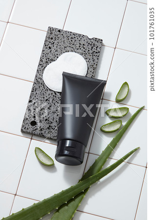 A stone podium with cotton pads and a black tube placed on, decorated with Aloe vera slices. Cosmetic product mockup of Aloe vera extract. It helps to eradicate skin blemishes and diminish age lines A stone podium with cotton pads and a black tube placed on, decorated with Aloe vera slices. Cosmetic product mockup of Aloe vera extract. It helps to eradicate skin blemishes and diminish age lines 101761035