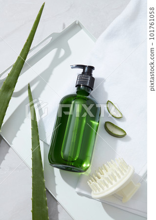 Mockup for shampoo product with green bottle unlabeled, comb, towel and fresh aloe vera on white background. Aloe vera contains many amino acids and proteolytic enzymes, vitamin that are good for hair 101761058